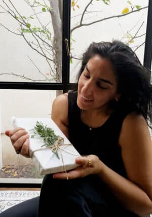 מורן אלחלל מחזיקה ספר עטוף בנייר אפייה בשיטת האוריגמי , תוצר של סדנת אוריגמי אריזות בסטייל לחגים בזום. סדנאות גיבוש לצוות, סדנאות לנשים, סדנאות יצירה מעשירות. moran alhalel holding a book packging in origami styling