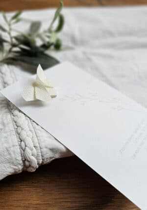 גלויית פבריאנו עם סיכת פרפר אוריגמי לבנה בטקסטורת משבצות עדינה, גלוית זיכרון מעוצבת, סיכת פרפר לבנה בד רשת, מורן אלחלל אוריגמי בד